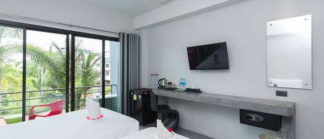 A hotel room with two beds, a TV, a coffee machine, and a view of palm trees.