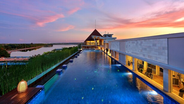 Piscina infinita en la azotea con vistas a un río y al atardecer.