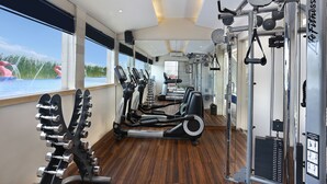 Un gimnasio con máquinas de cardio, máquinas de pesas y vistas a un cuerpo de agua.