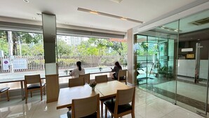 A modern indoor space with glass walls, wooden tables, and chairs. - S3 Residence Park (Bangkok)
