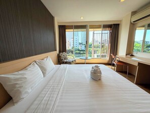 Een hotelkamer met een groot bed, een bureau, een stoel en uitzicht op de stad.