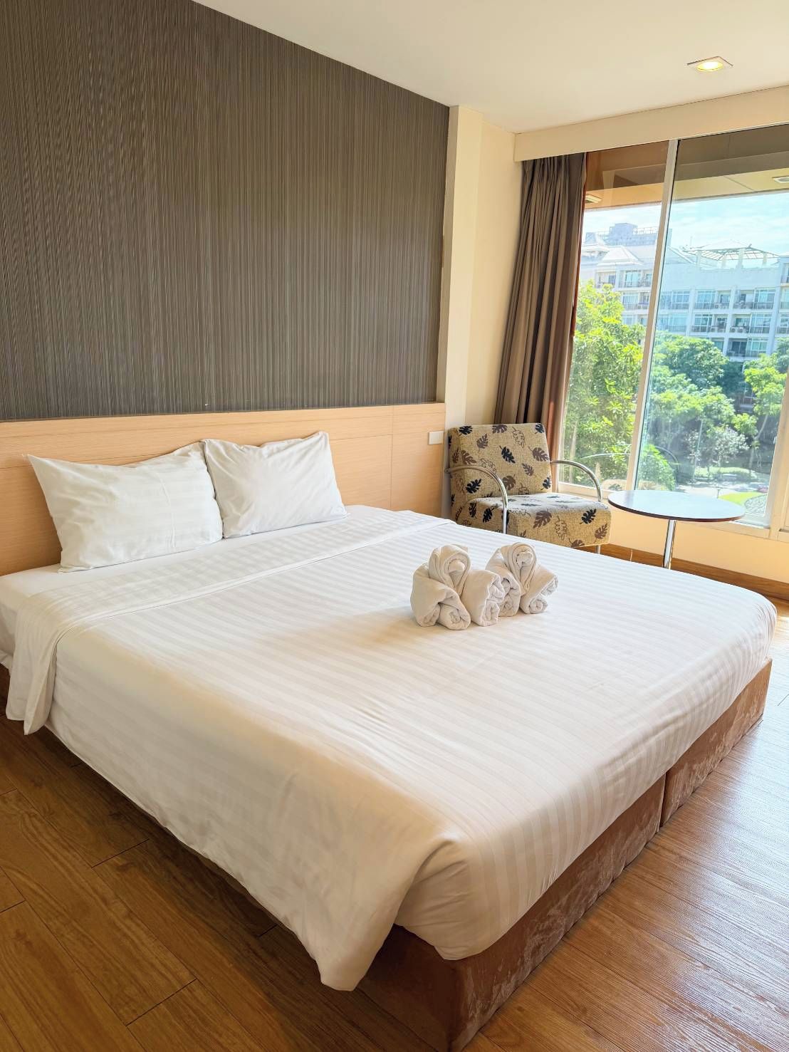 A hotel room with a large bed, a small table, and a chair.