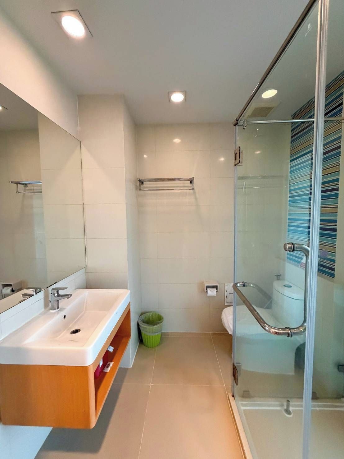 A modern bathroom with a glass shower enclosure, a sink with a mirror, and a toilet.