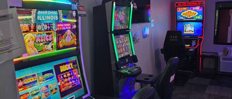 A room with multiple gaming machines, including 'Game Chest Illinois' and 'Rocky', and a 'VIP Lounge' sign.