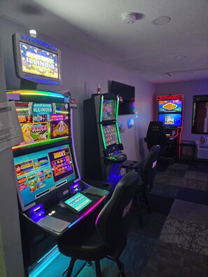 Una sala con múltiples máquinas de juego, incluyendo 'Game Chest Illinois' y 'Rocky', y un letrero que dice 'VIP Lounge'.
