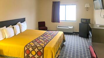 Relax in this inviting room with a large bed, comfortable chair, and desk area featuring a TV.
