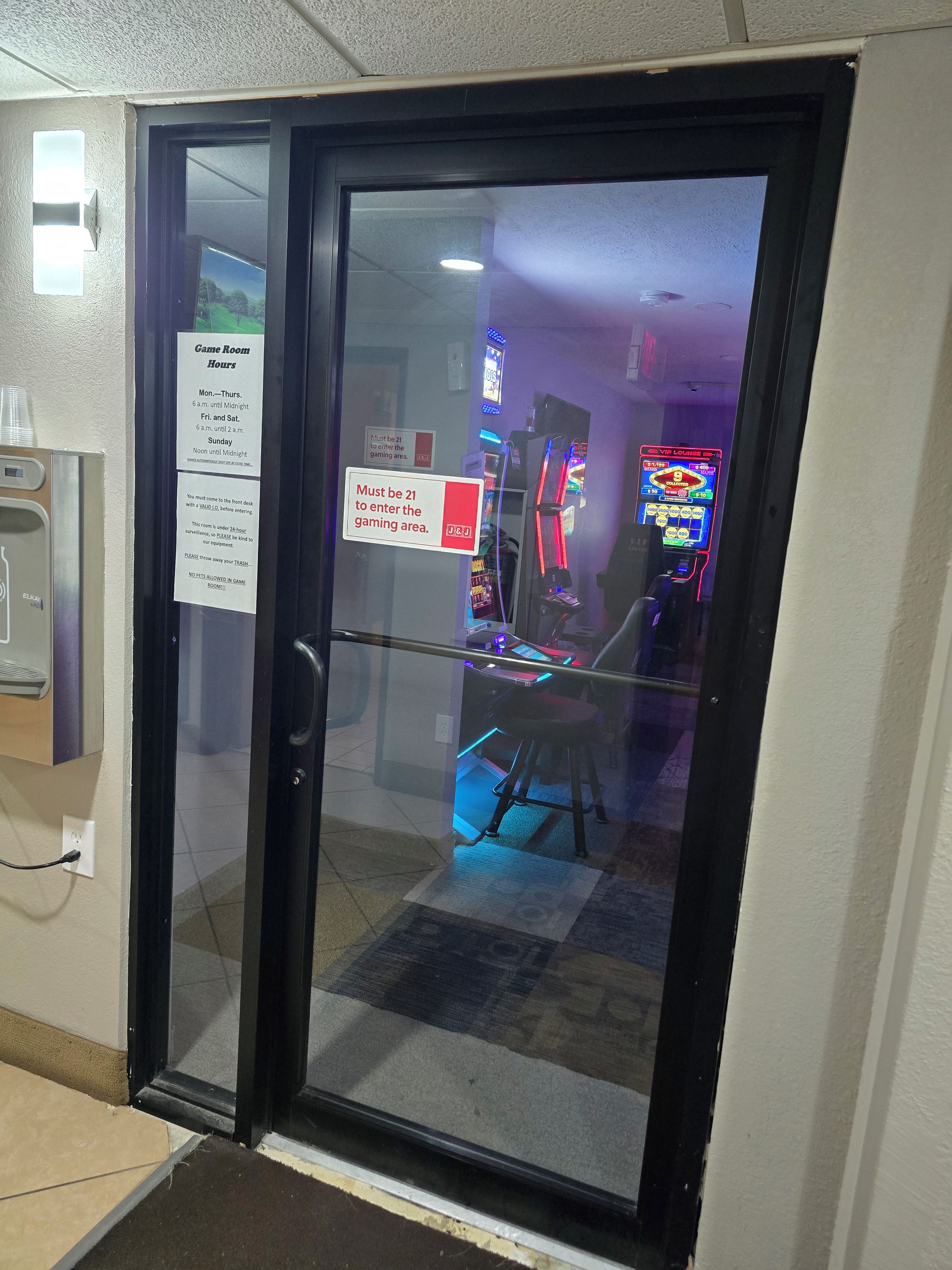 Una puerta de vidrio conduce a un área de juegos con luces de neón y máquinas tragamonedas.