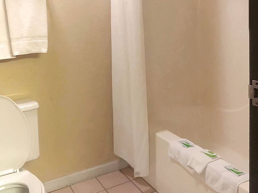 A bathroom with a toilet, a shower curtain, and a towel rack with towels.
