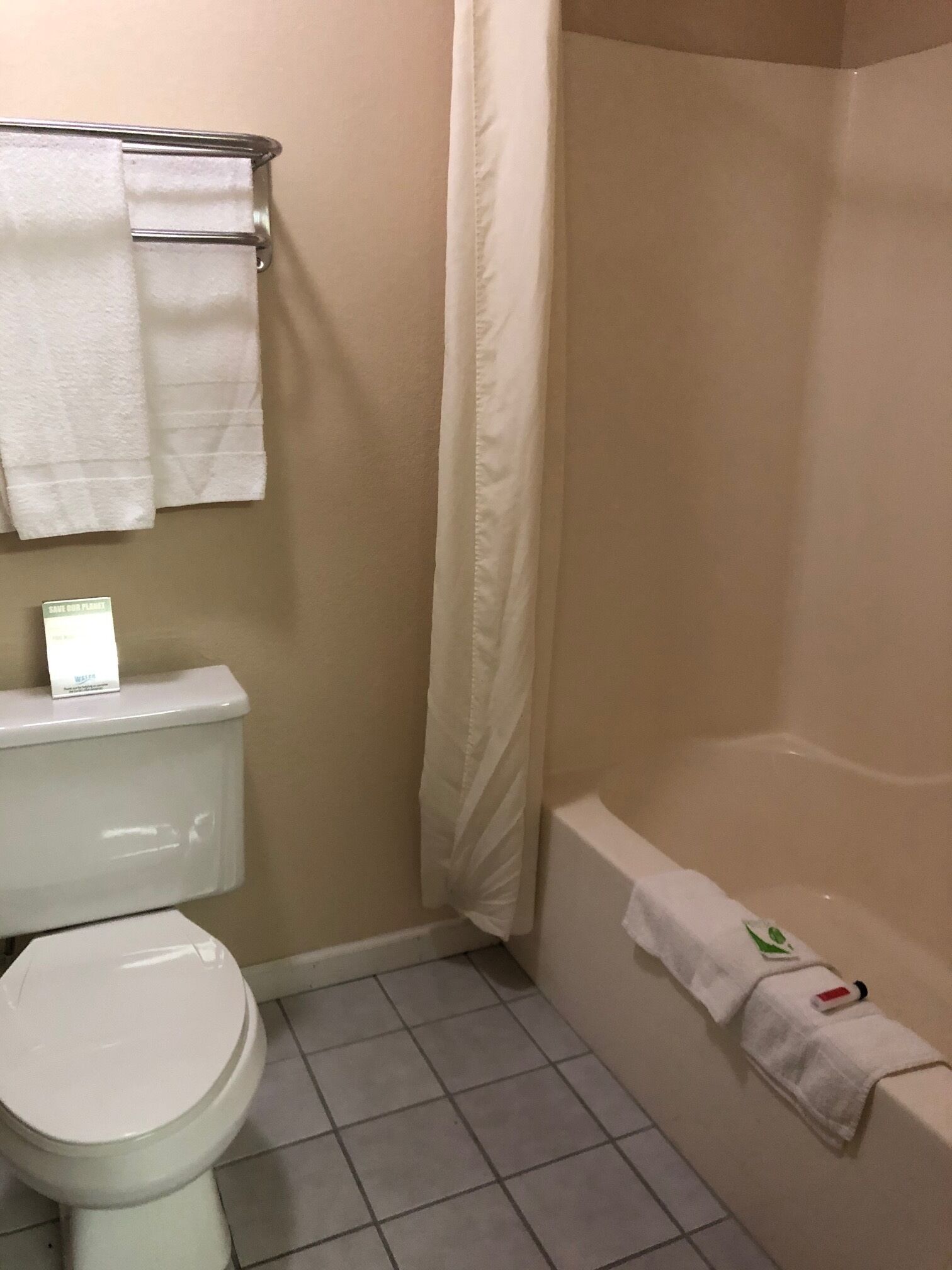 A bathroom with a toilet, a shower, and a towel rack.