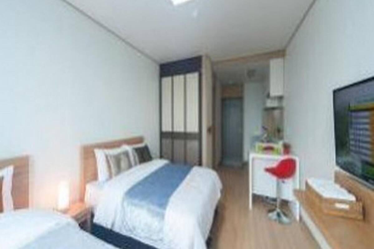 Moderni hotellihuone, jossa on kaksi sänkyä, työpöytä ja televisio.