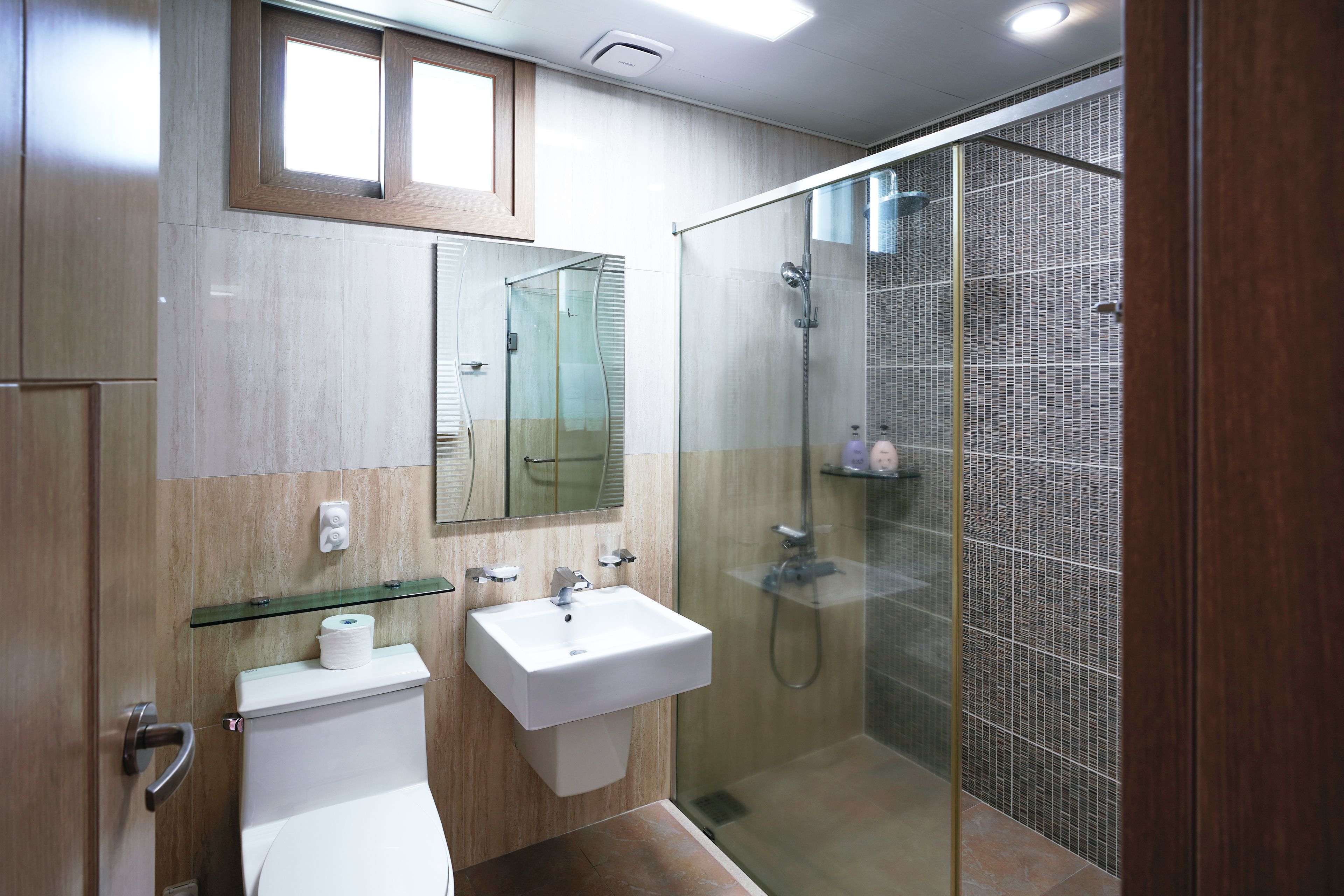 Un baño moderno con cabina de ducha de vidrio, un lavabo blanco y un inodoro.