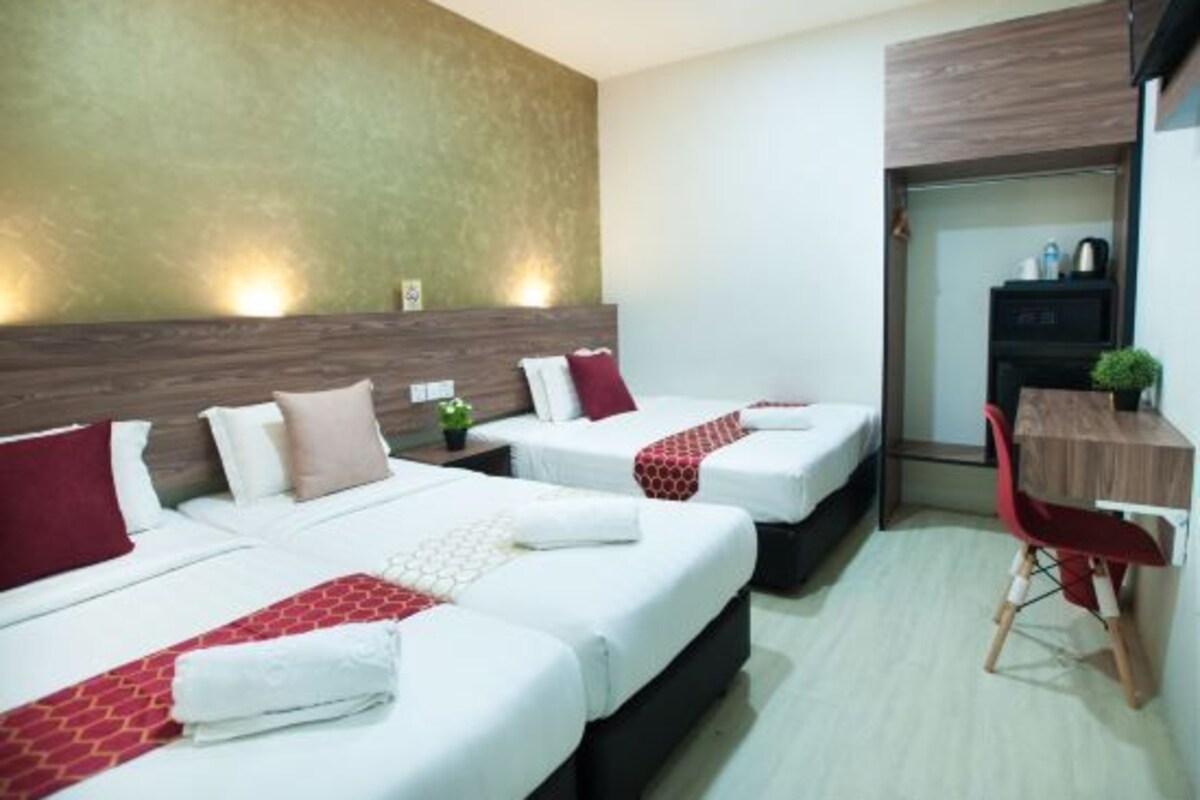 Une chambre d’hôtel avec deux lits, un bureau et une chaise.