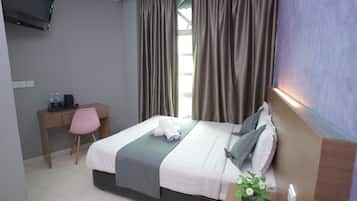 Een hotelkamer met een bed, een bureau, een stoel, een televisie en een raam met gordijnen.