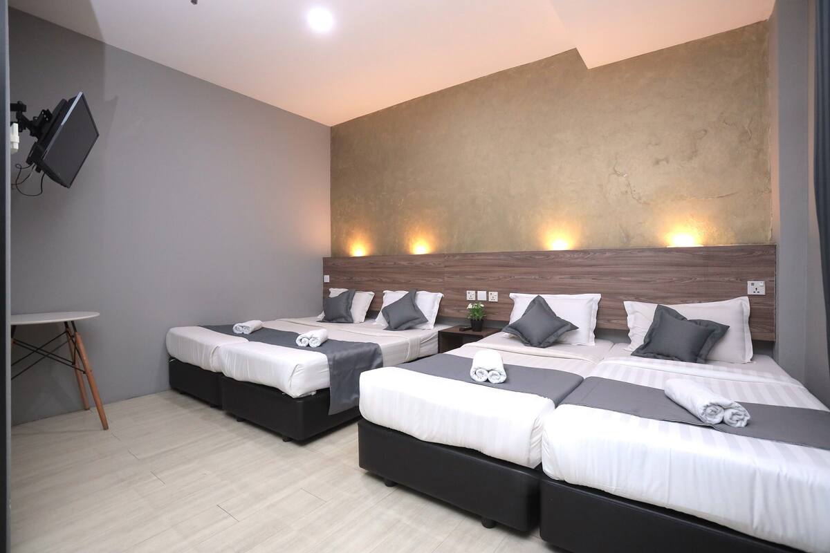A hotel room with two beds, a desk, and a TV mounted on the wall.