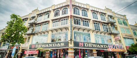 A multi-story building with a prominent 'DEWANDAS' sign, indicating a textile center.