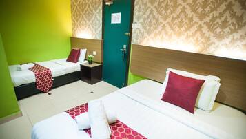 A hotel room with two beds, a green wall, patterned wallpaper, and a door with a sign.