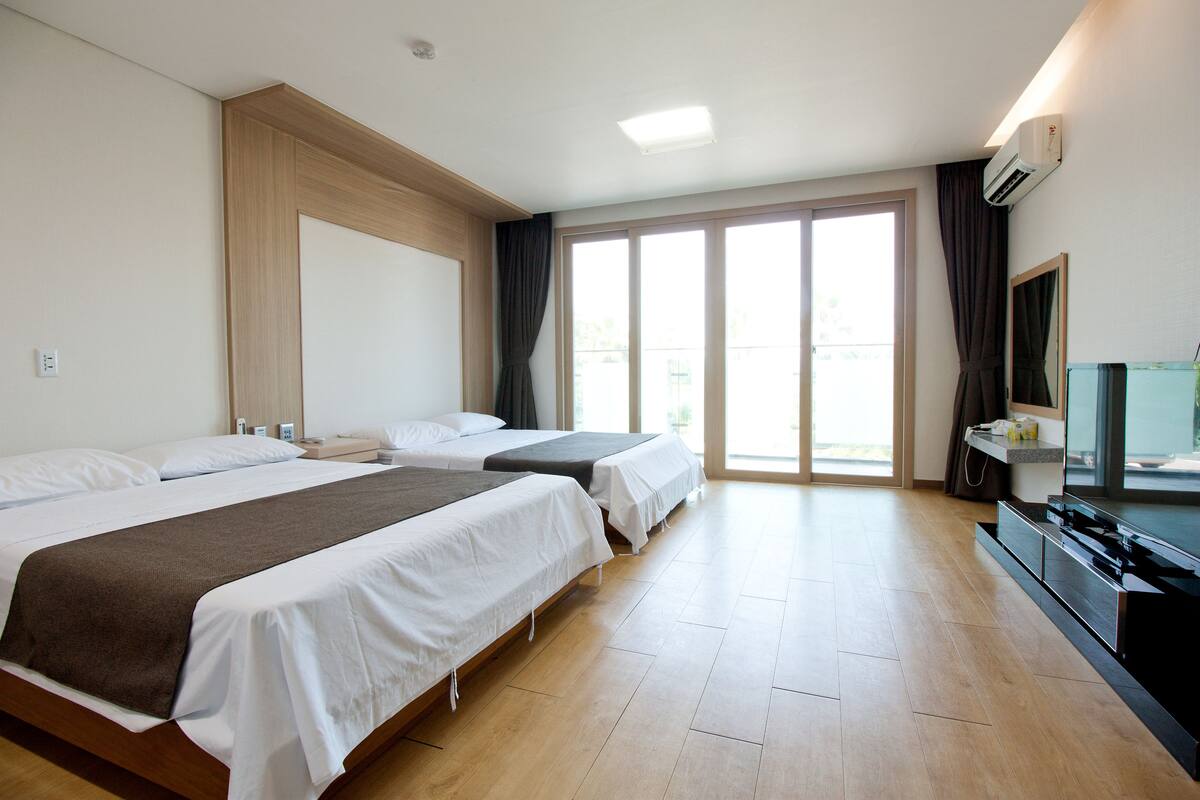 Hotellihuone, jossa on kaksi sänkyä, suuri ikkuna, televisio ja minibaari.