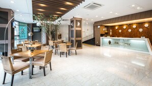 Un moderno vestíbulo de hotel con mostrador de recepción de madera, zona de estar y una escalera.