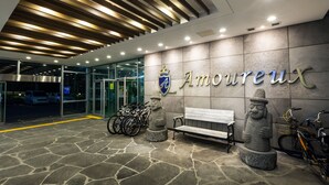Entrada con piso de piedra, un banco, una estatua y un letrero en la pared que dice 'Amoureux'.