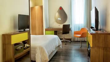 A hotel room with a bed, desk, chair, television, and a unique wall decoration.