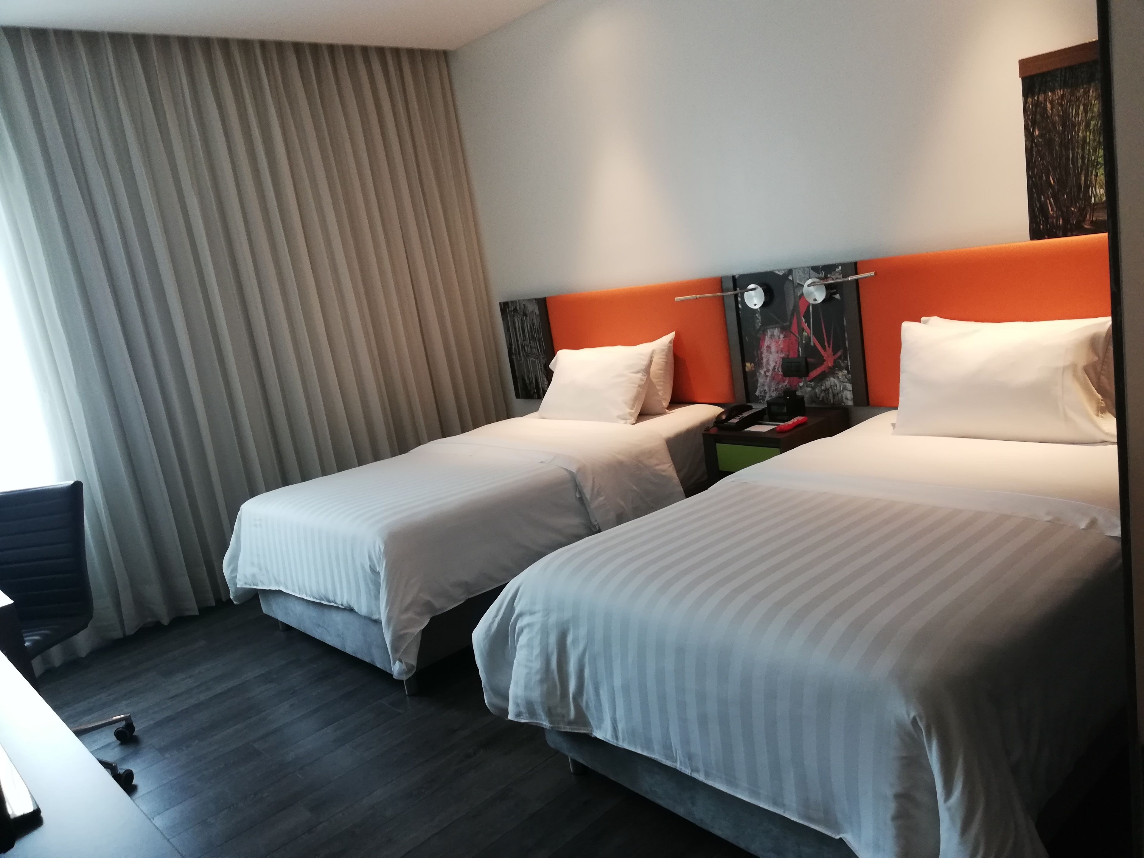 A hotel room with two beds, a desk, and a chair.