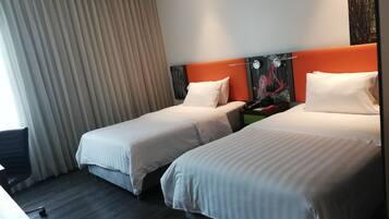 A hotel room with two beds, a desk, and a chair.