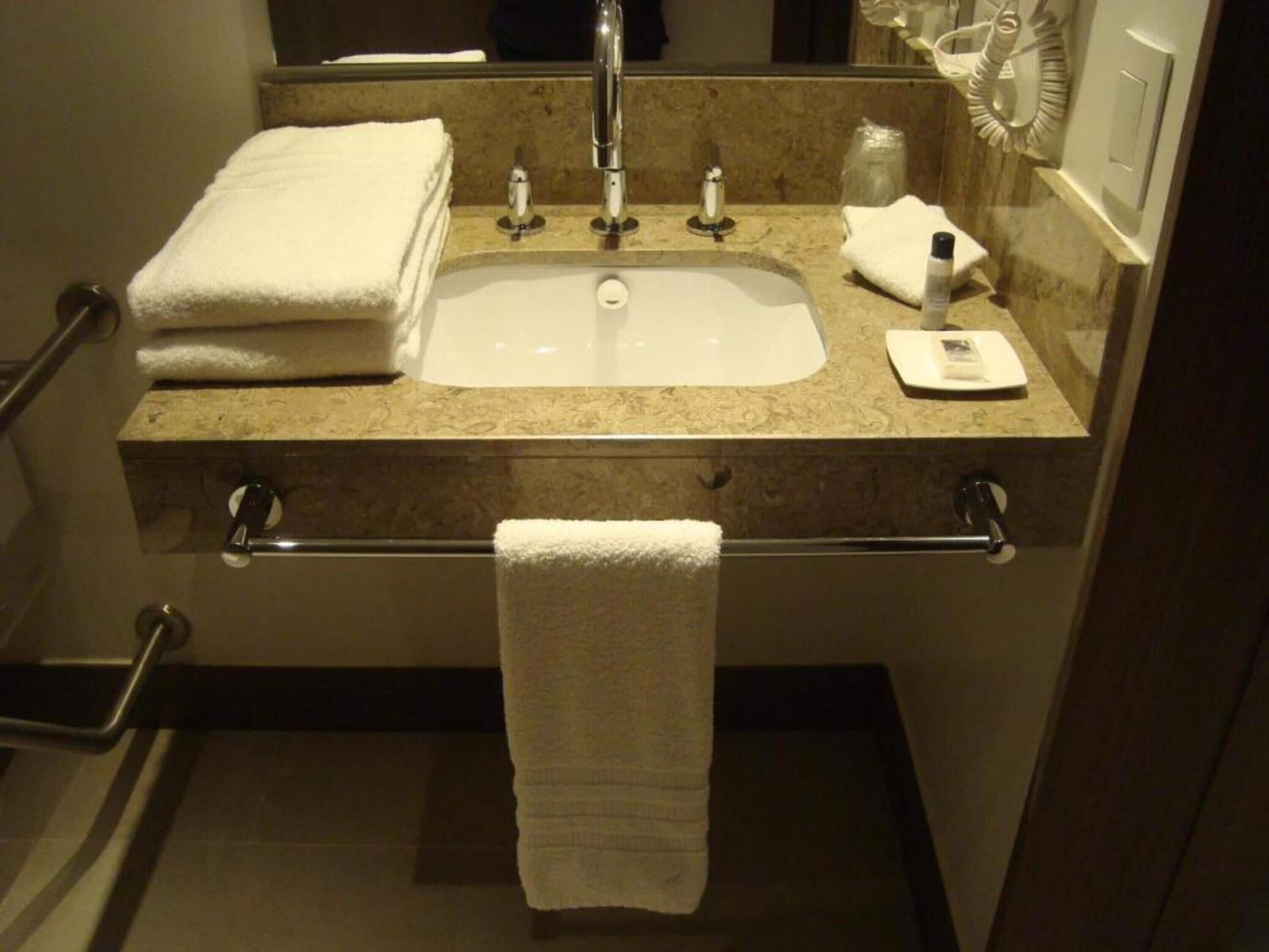 A bathroom with a sink, two towel racks, and a mirror.