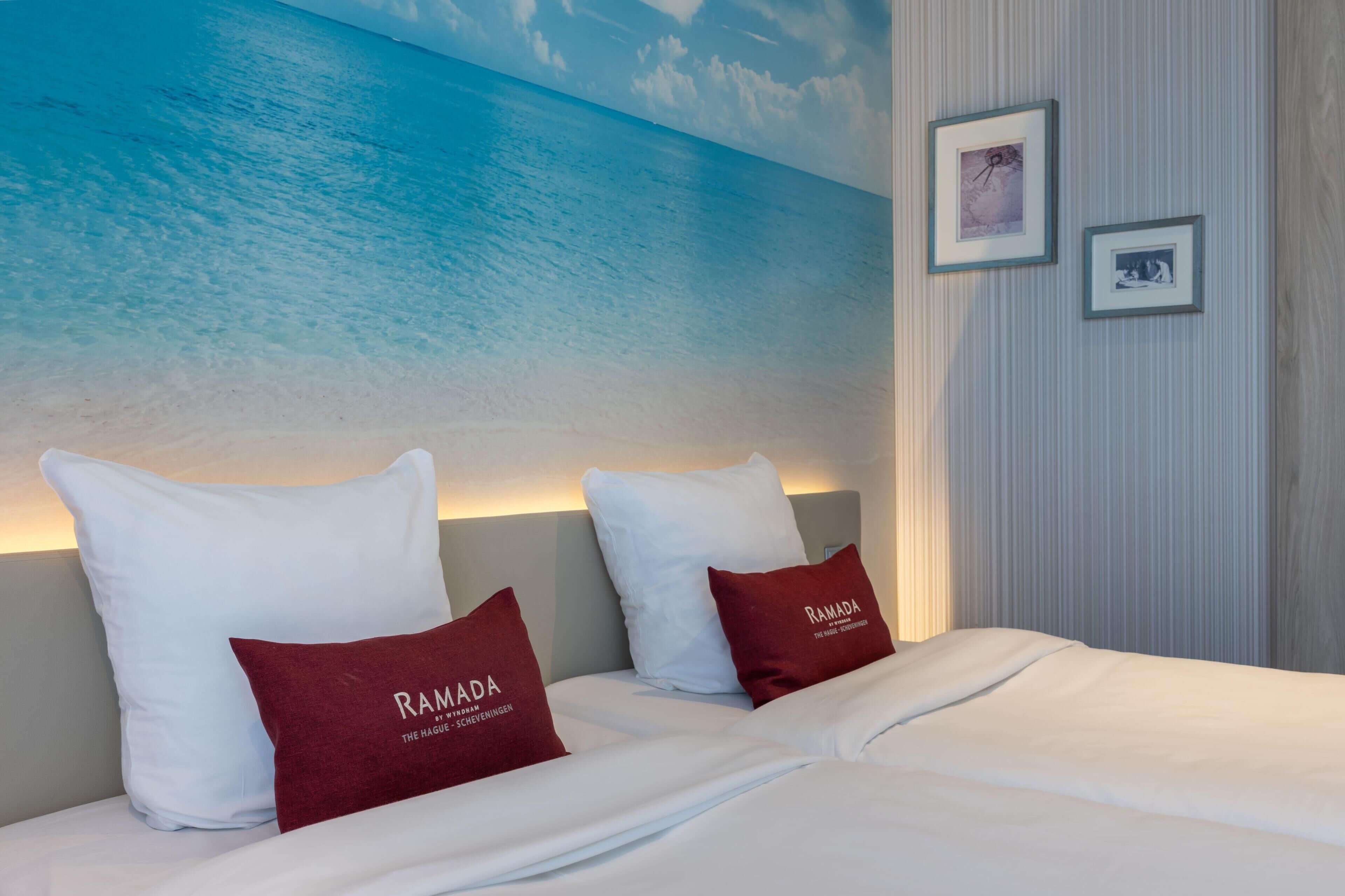 Una habitación de hotel con cama, almohadas, un mural en la pared y cuadros enmarcados.