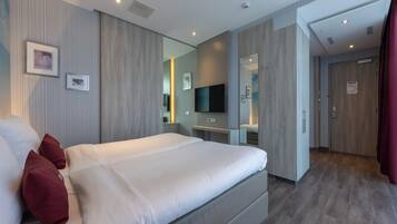 A modern hotel room with a large bed, a flat-screen TV, a bedside table, and a mirror.