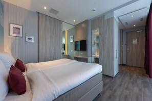 Een moderne hotelkamer met een groot bed, een flatscreen televisie, een nachtkastje en een spiegel.