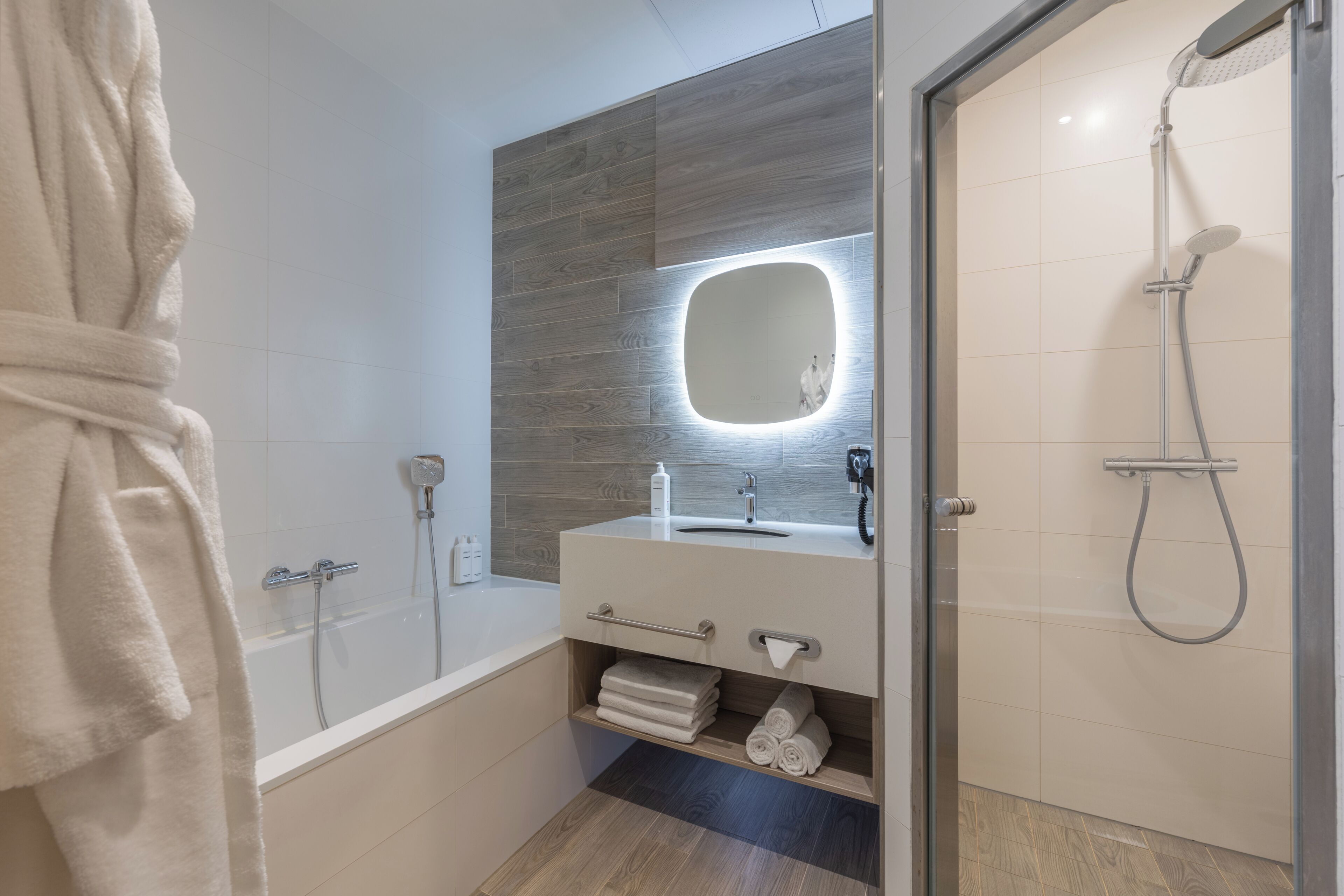 Ein modernes Badezimmer mit Badewanne, Dusche, Waschtisch mit Spiegel und Handtuchhalter.