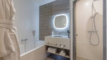Ein modernes Badezimmer mit Badewanne, Dusche, Waschtisch mit Spiegel und Handtuchhalter.