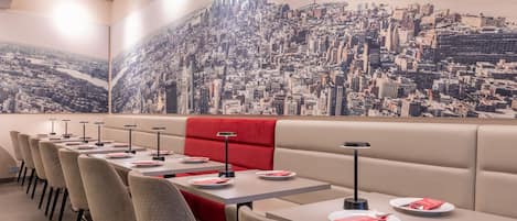 A restaurant with a cityscape mural, booths, and tables with plates and cutlery.