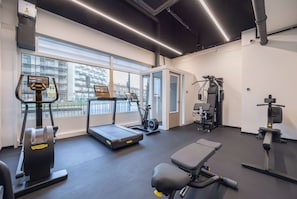 Ein modernes Fitnessstudio mit Laufbändern, Krafttrainingsgeräten und einer Bank.