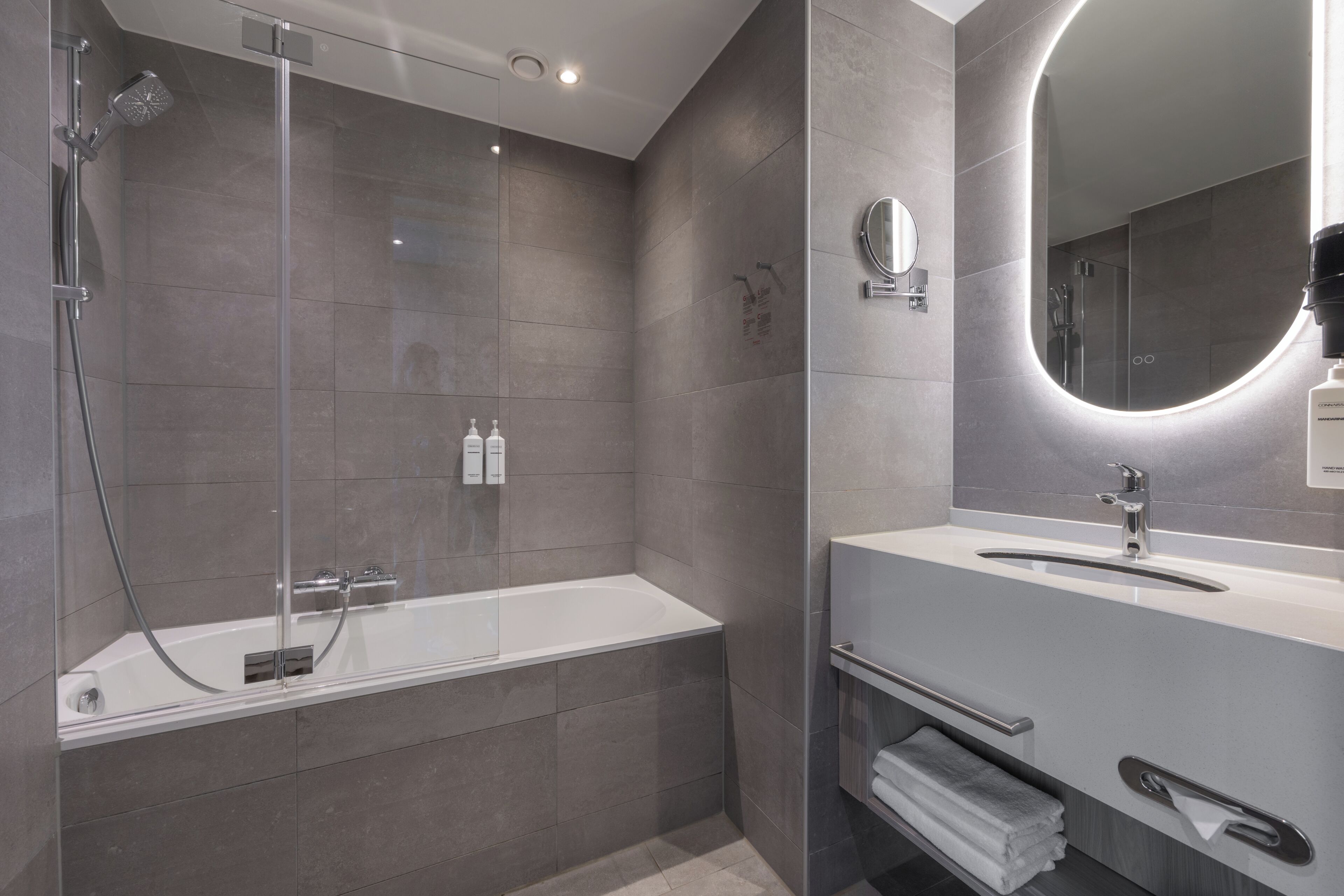 Une salle de bain moderne avec une douche à parois de verre, une baignoire blanche et un meuble-lavabo avec un miroir.