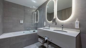 Ein modernes Badezimmer mit zwei Waschbecken, einer Duschkabine aus Glas und einem Handtuchhalter.