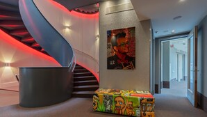 Un intérieur moderne avec un escalier en colimaçon, une affiche au mur et un banc coloré.