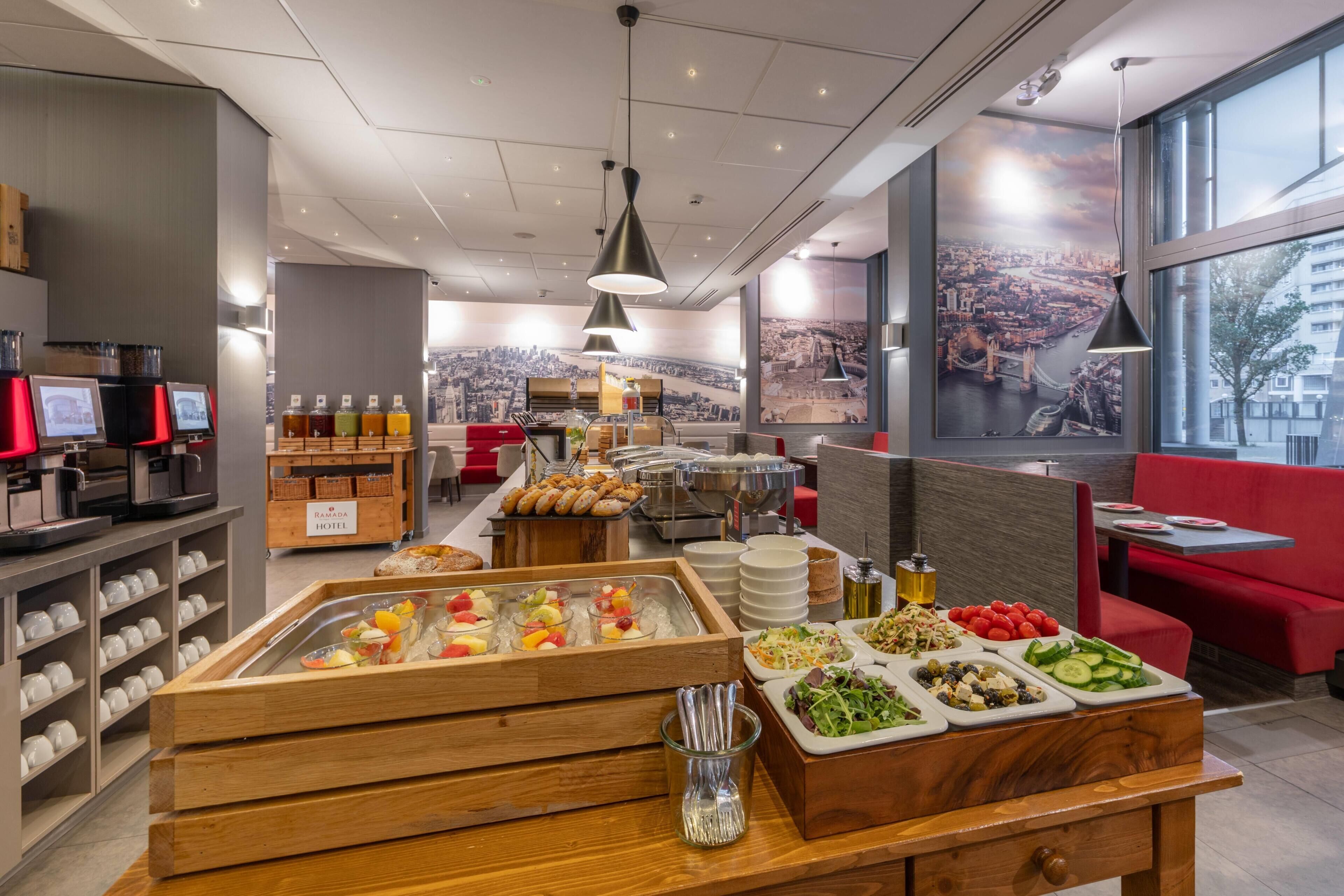 Un espace dédié au petit-déjeuner dans l’hôtel, proposant une variété d’aliments, notamment des fruits, des viennoiseries et des boissons.