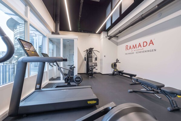 Ein modernes Fitnessstudio mit Laufbändern, einer Langhantelbank und Kraftgeräten.