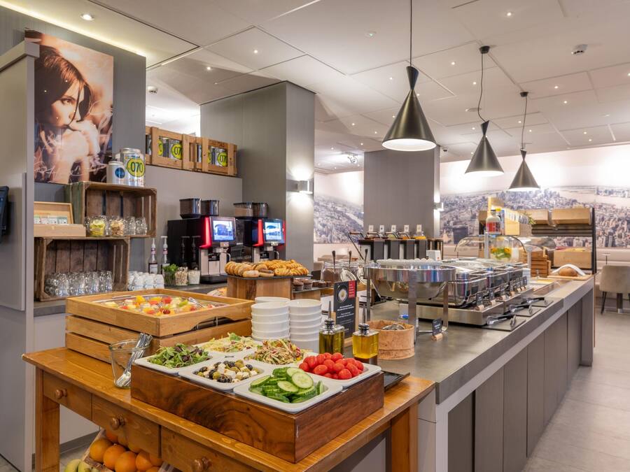 A buffet area with various food options, a coffee station, and a cityscape view.