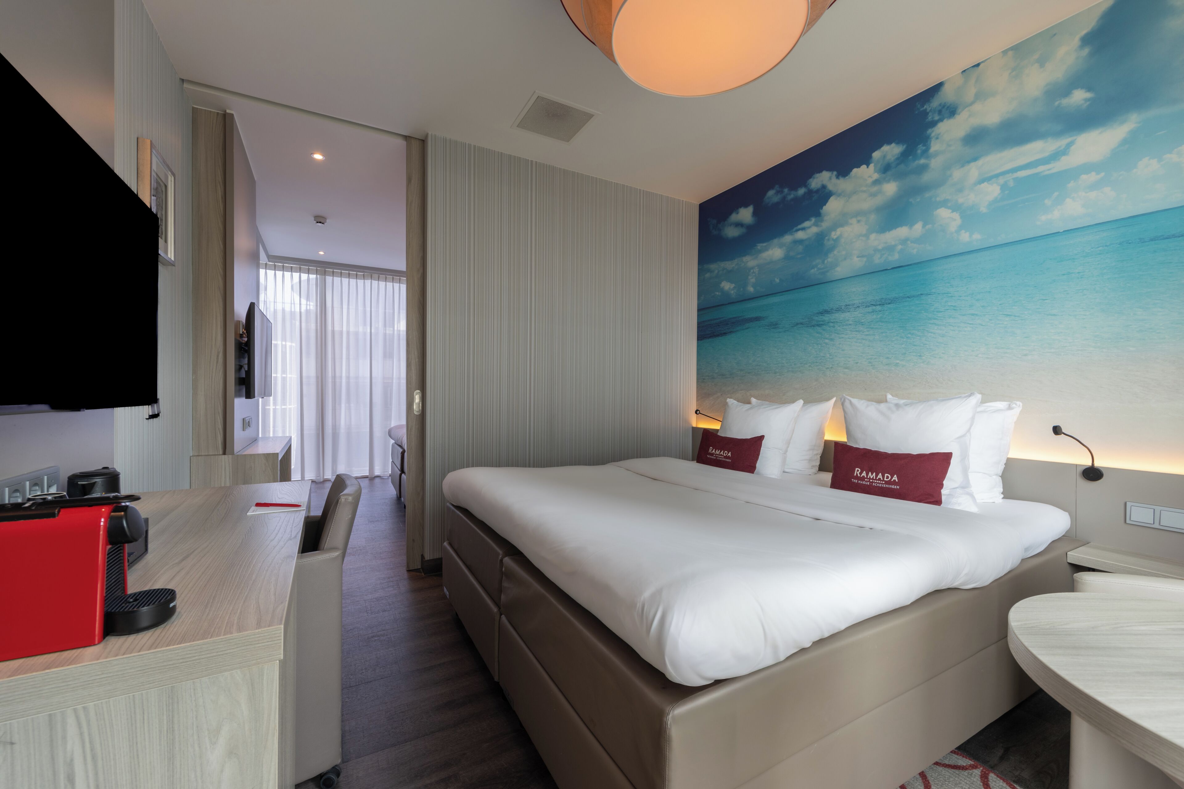 A hotel room with a large bed, a desk, and a television.
