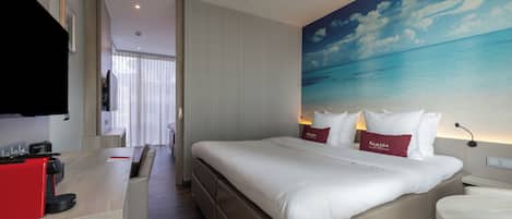 A hotel room with a large bed, a desk, and a television.