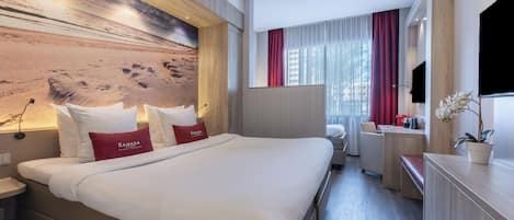 Habitación de hotel con una cama grande, un escritorio, un televisor y vistas a la playa.