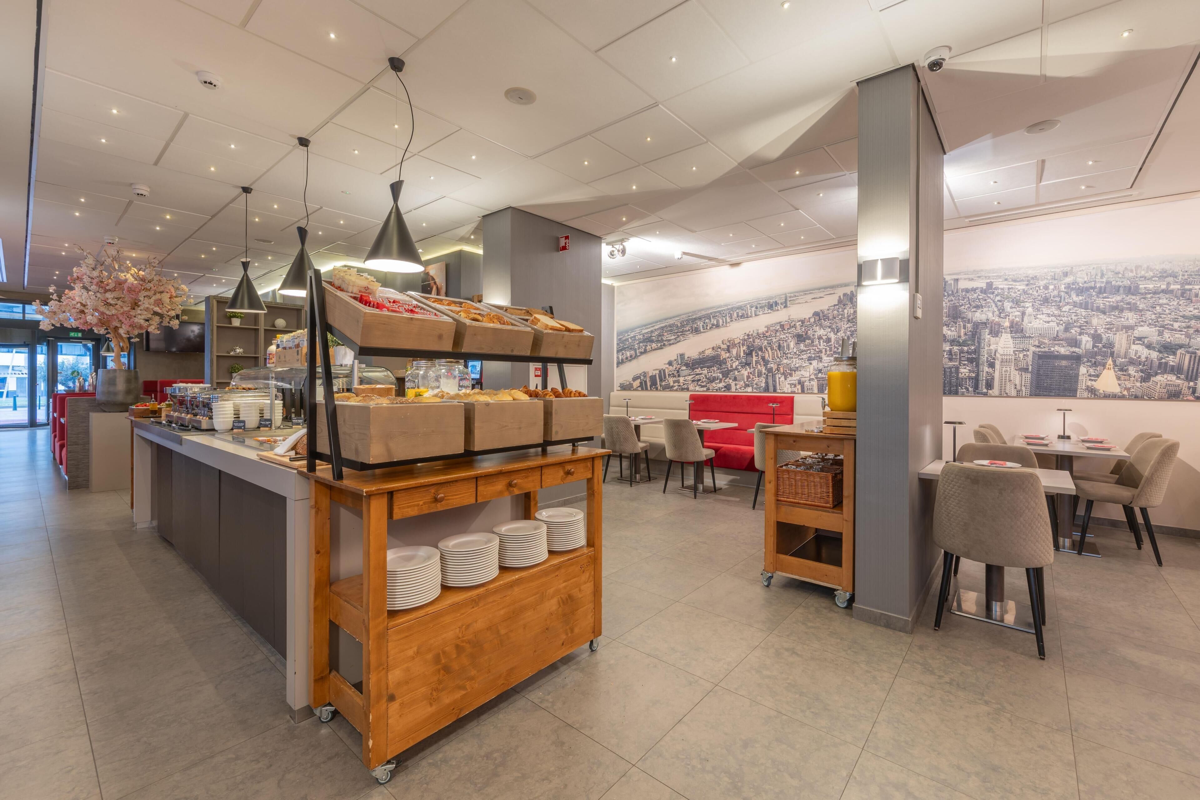 Een modern café met een buffet, een zithoek en een stadsgezicht muurschildering.