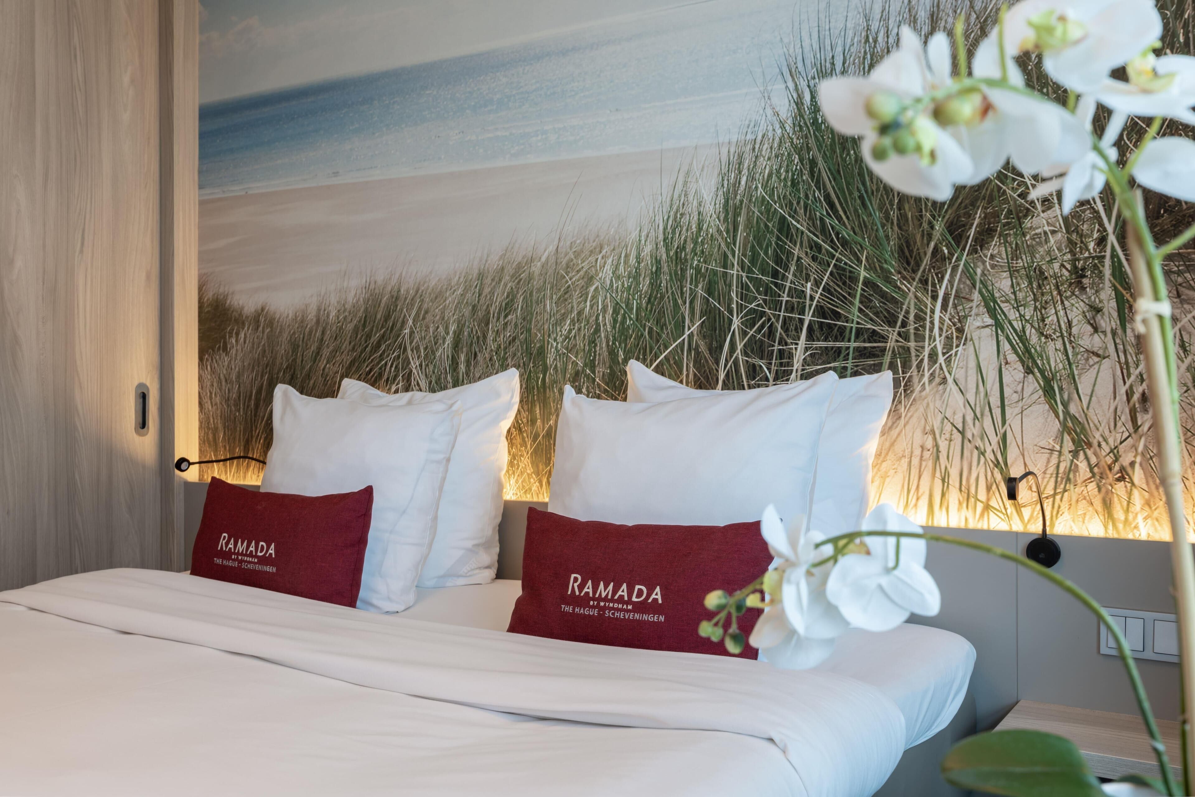 Habitación de hotel con una cama, almohadas blancas y un mural en la pared.