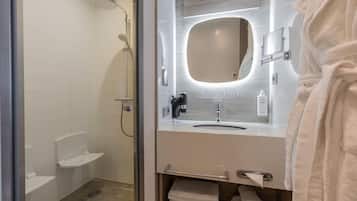 A modern bathroom with a glass-enclosed shower, a vanity with a mirror, and a towel rack.