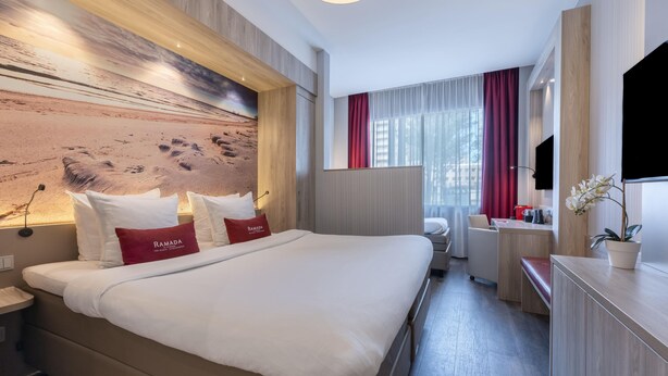 Une chambre d’hôtel avec un grand lit, un bureau, une télévision et une vue sur la plage.