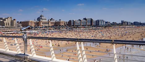 A beach with a boardwalk and a large building with a dome in the background.