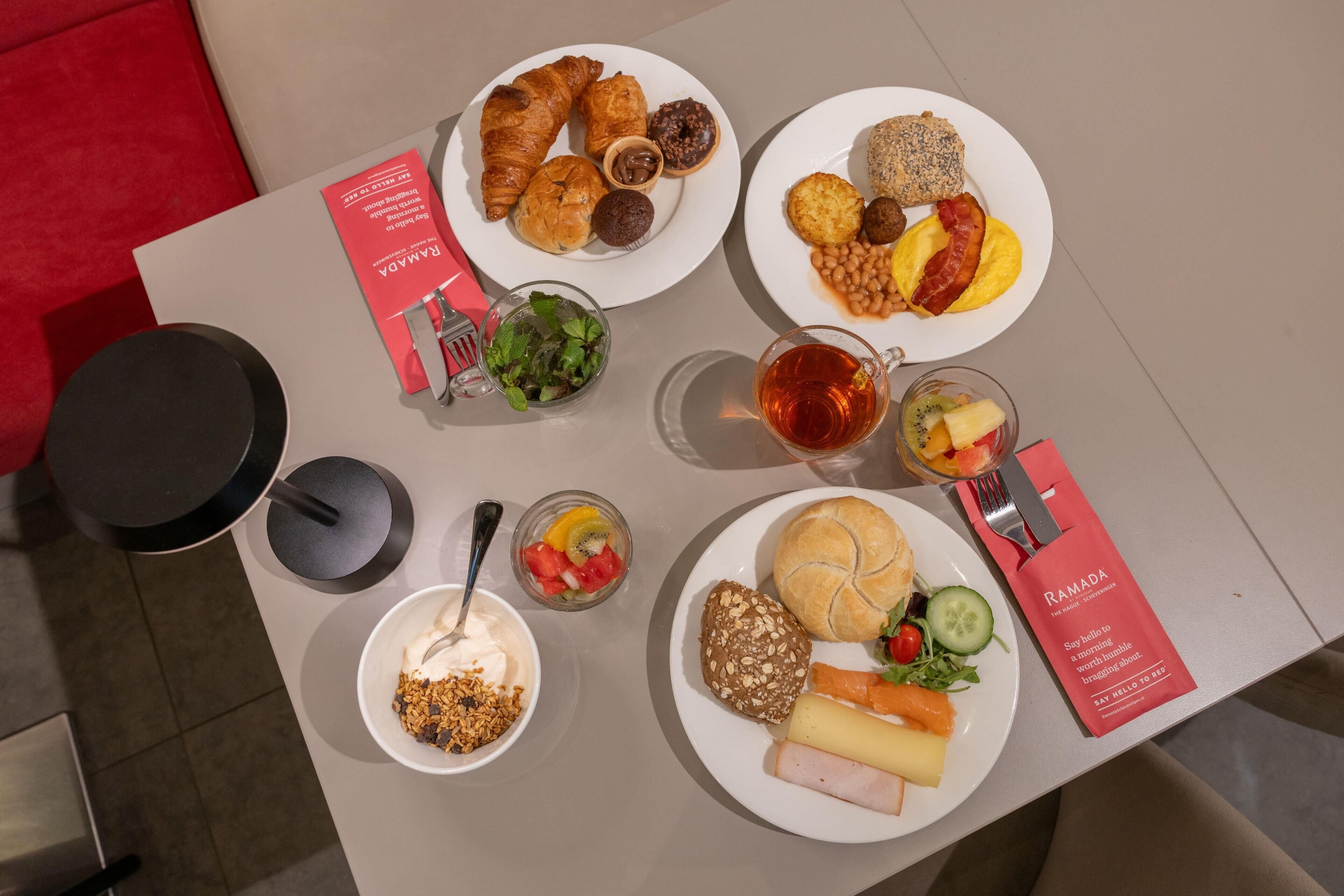 Taula amb diferents plats per esmorzar, com croissants, muffins i un plat amb ous, tocínet i fesols.