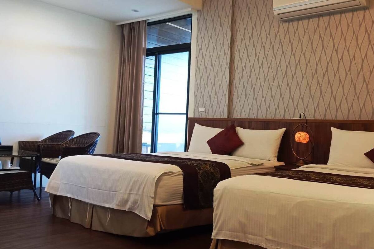 A hotel room with two beds, a desk, and a chair.